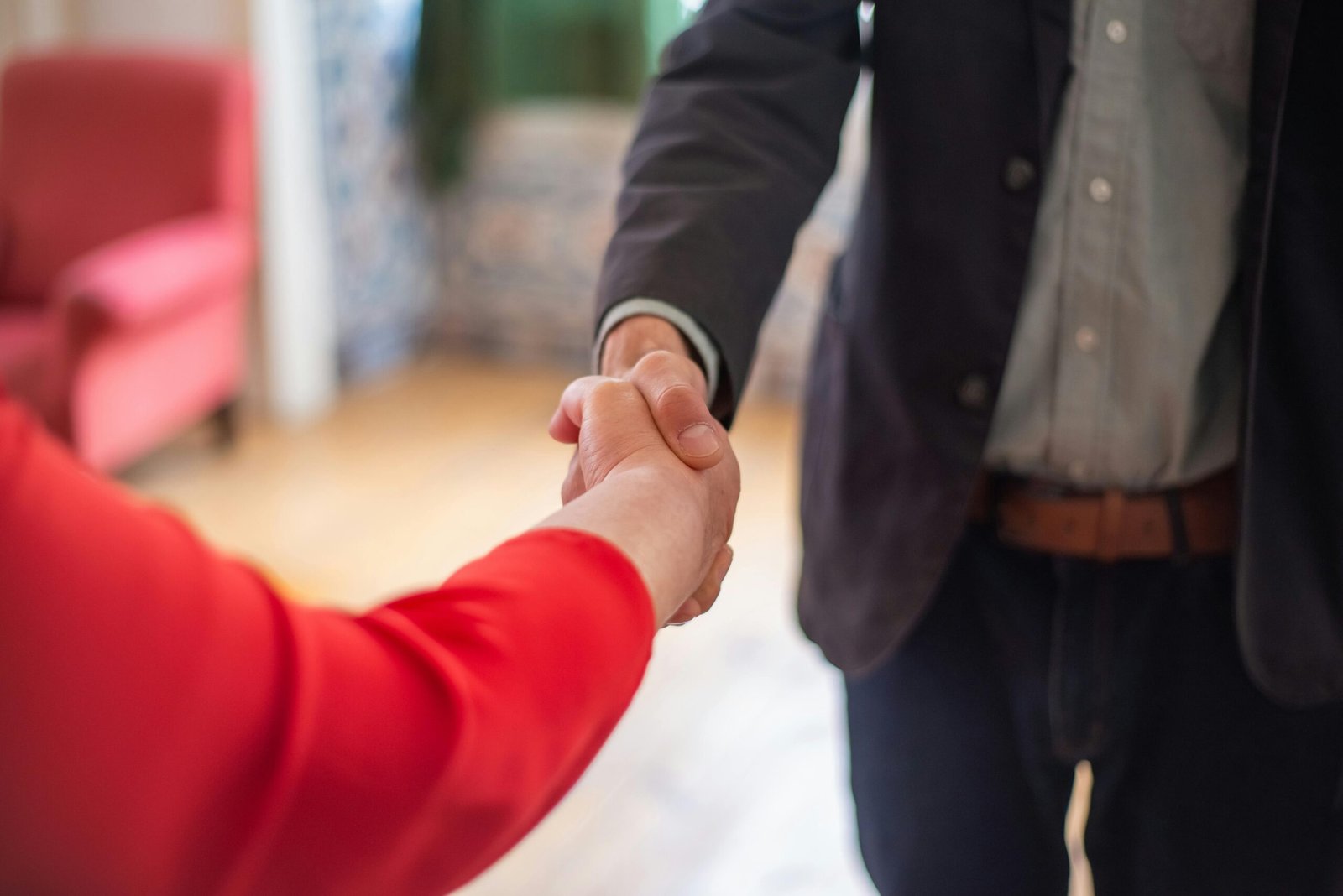 Home Close-up view of two people shaking hands indoors, symbolizing agreement or partnership.